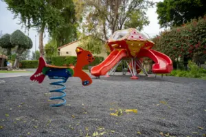 גן משחקים עם קפיצת חתול צבעונית ומגלשה אדומה בצורת חללית