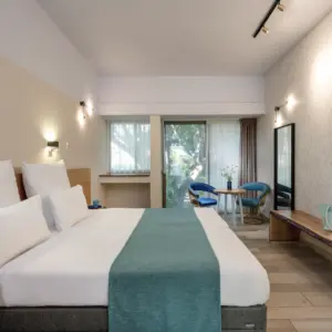 חדר שינה מרווח עם מיטה זוגית, פינת ישיבה וחלון גדול.